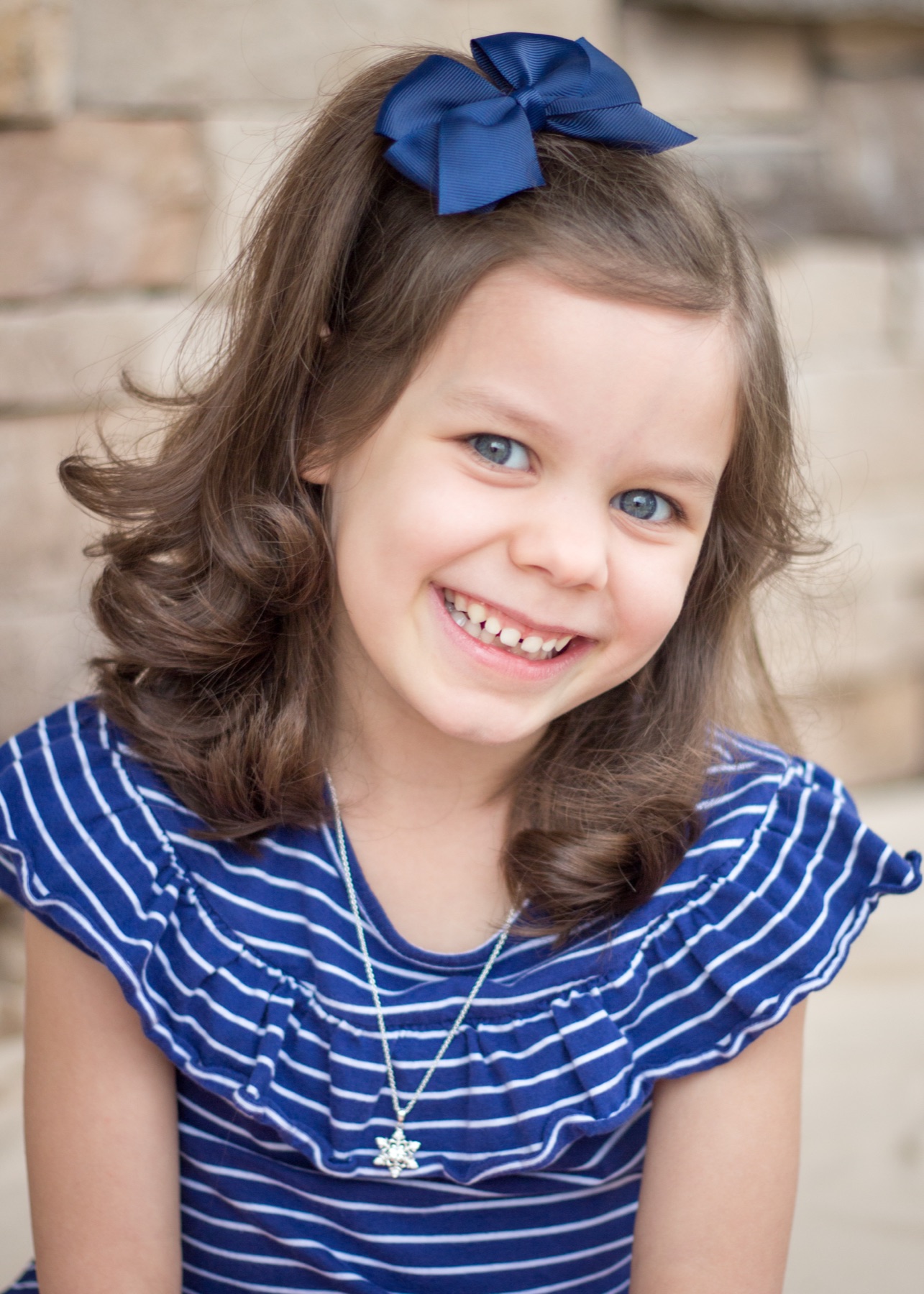 Young girl smiling with a navy bow in her hair